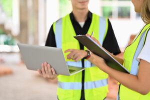 Aufsichtsbehörde für Arbeitsschutz kontrolliert Betrieb – Mitarbeiter besprechen Maßnahmen mit Laptop und Checkliste